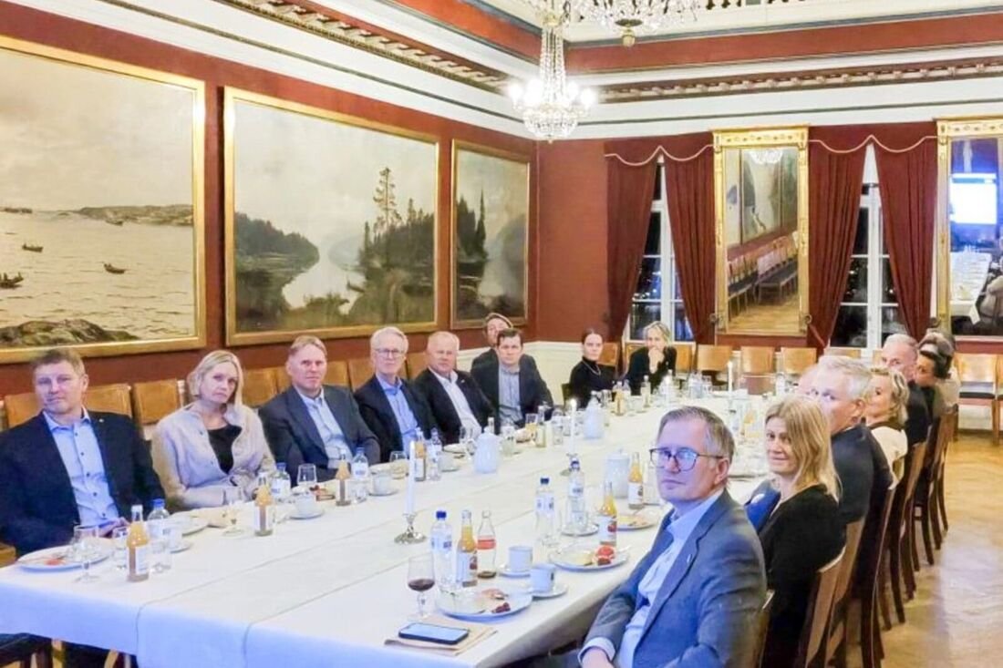 Deltakere samlet rundt et langbord i en konferansesal