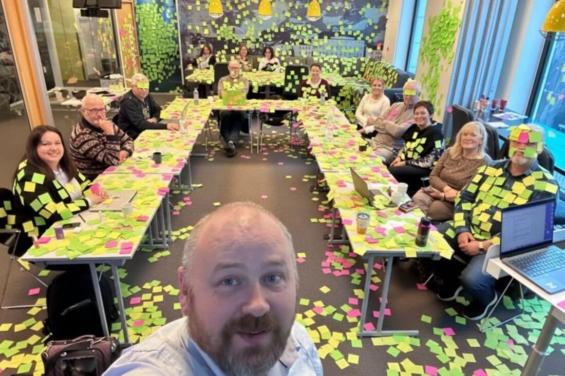 Workshop med deltakere rundt et bord dekket av notater